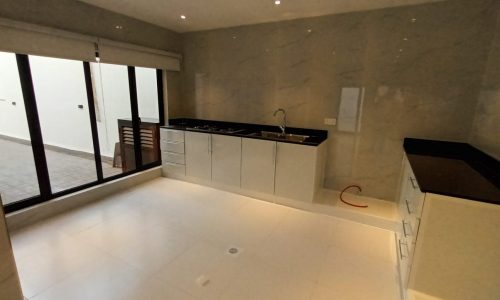 A spacious kitchen with white cabinets and a sliding glass door in a luxury villa.