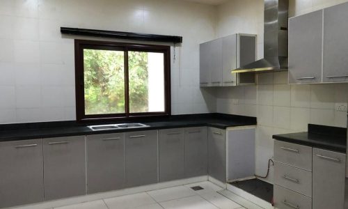 A luxurious kitchen in the Al Jasra villa with elegant grey cabinets and a beautiful window.