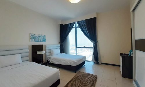 A fully furnished 2BR apartment with sea view, featuring two beds and a flat screen TV.