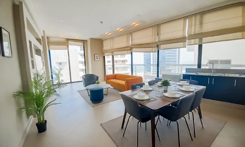 A fully furnished 2BR apartment with a living room and dining area, offering a view of the city.