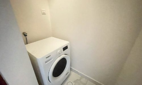 A brand new washing machine is sitting in a small room.