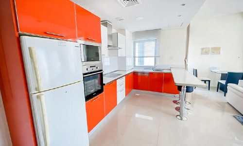 Luxury apartment for rent in Al Mahooz area with a kitchen featuring orange cabinets and white appliances.