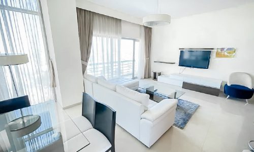 A luxury apartment for rent in Al Mahooz area with white furniture and a flat screen tv.