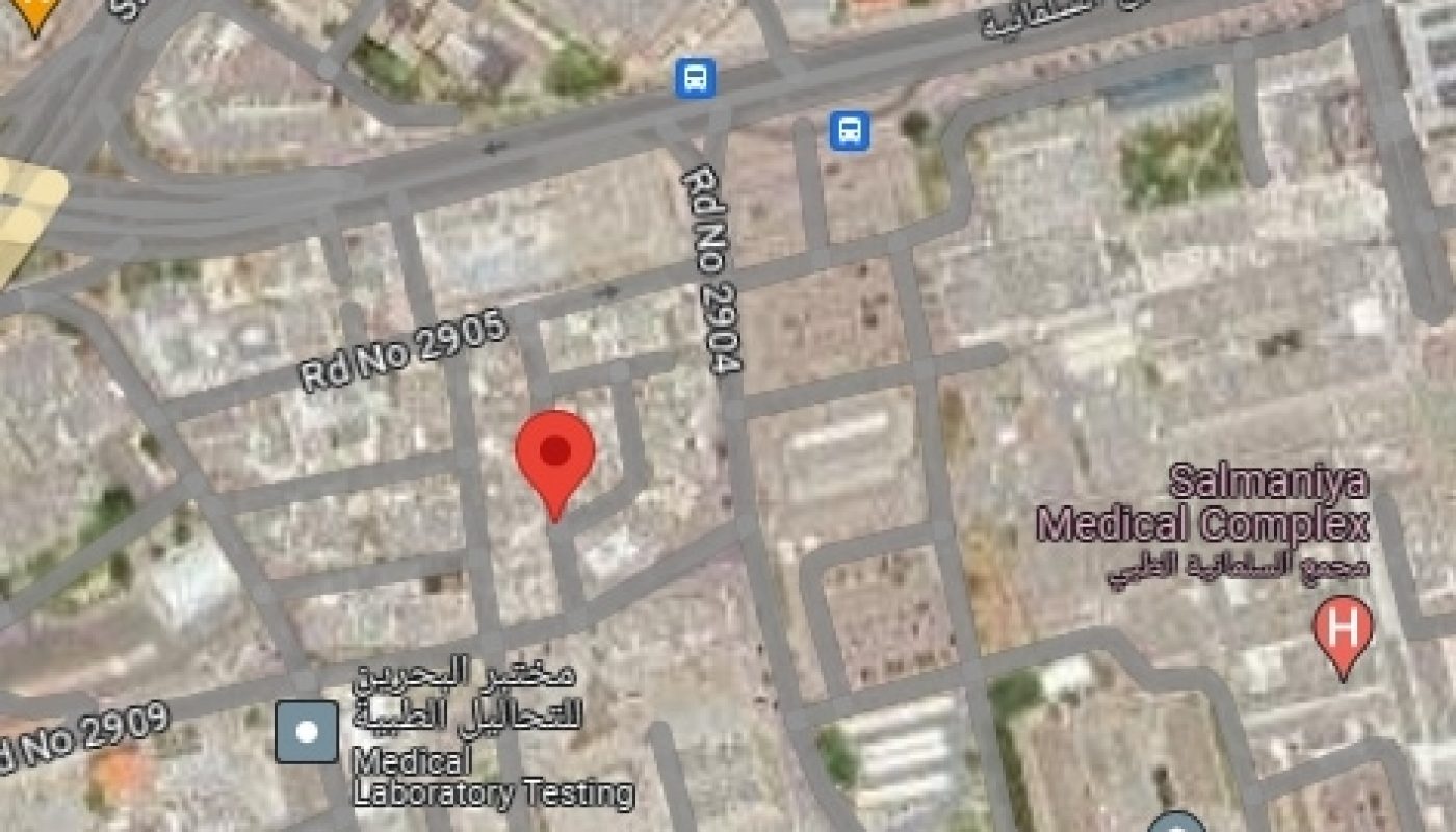 Satellite view of an urban area with streets and buildings, featuring a red pin marker indicating a specific location.