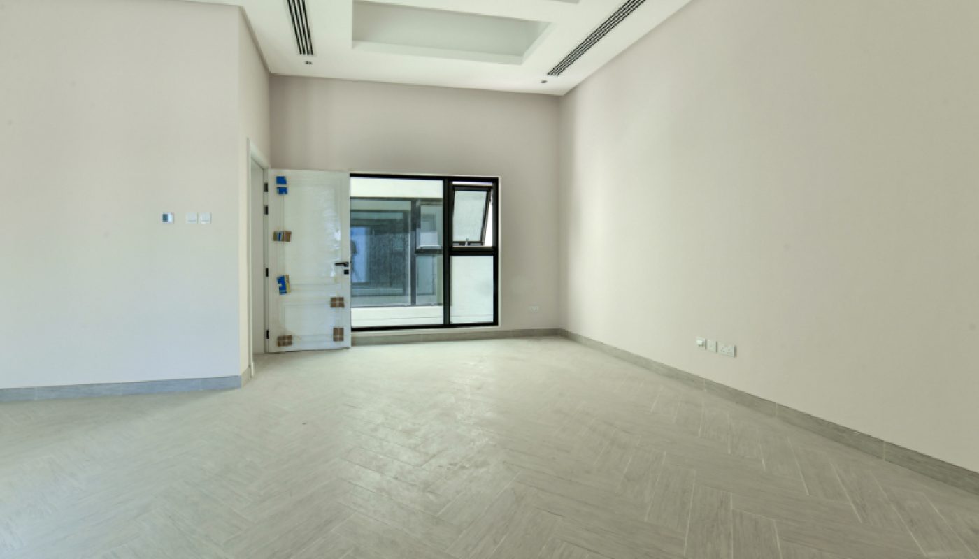 Empty, modern room with light-colored walls and tile flooring, a partially open door, and a large window letting in natural light.