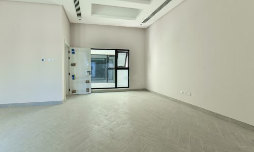 An empty room with wooden floors and a door in a Luxury 5BR Villa for Sale in Janabiyah.