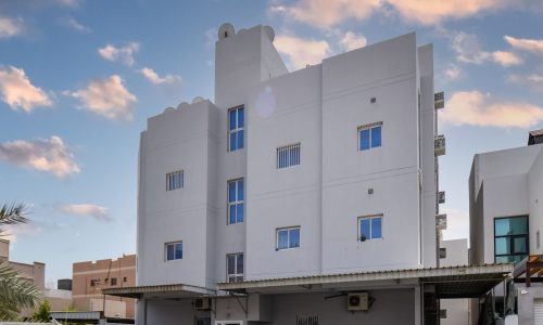 Keywords: White building, cars parked.