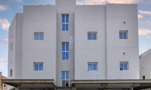 A white building with two cars parked in front of it in Roundabout 13 Hamad Town Bahrain.