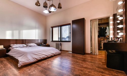 Furnished bedroom with wooden floors and a bed.