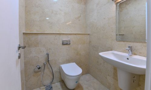 A bright bathroom fitted with a toilet, sink, and mirror.