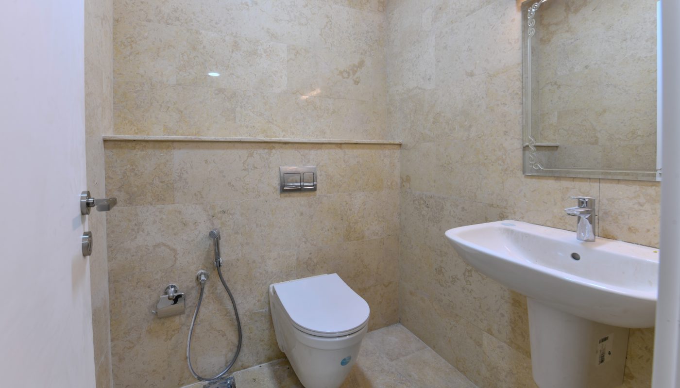 A bright bathroom fitted with a toilet, sink, and mirror.