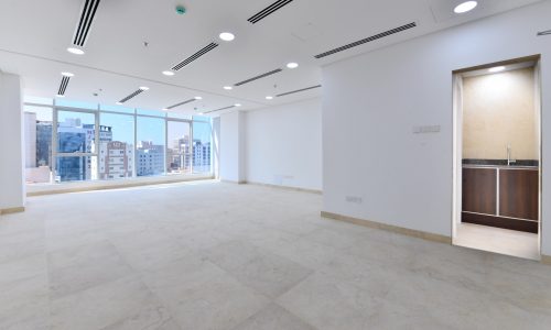 A bright empty room with a view of the city in a new building in the heart of Seef.