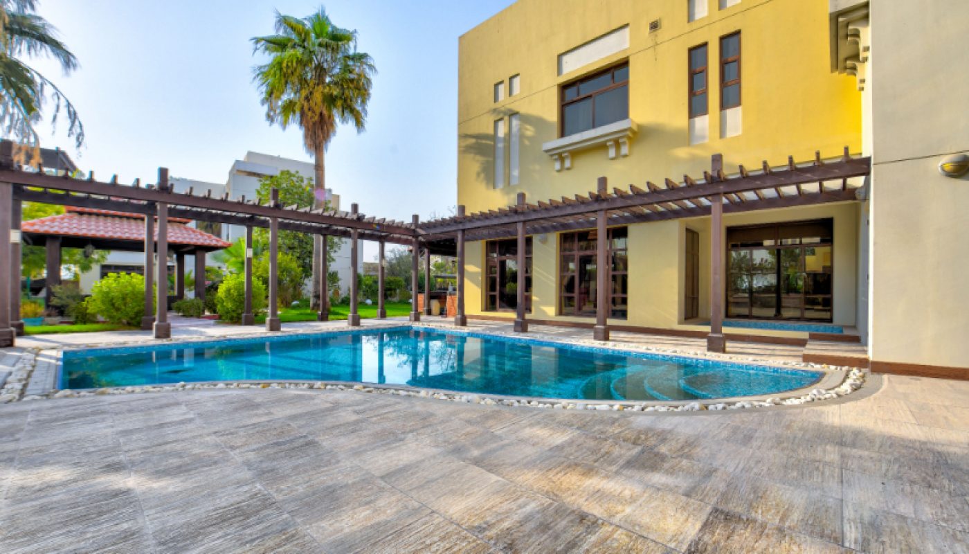 Modern house with large windows, a pergola, and a swimming pool in the backyard, surrounded by greenery and palm trees.