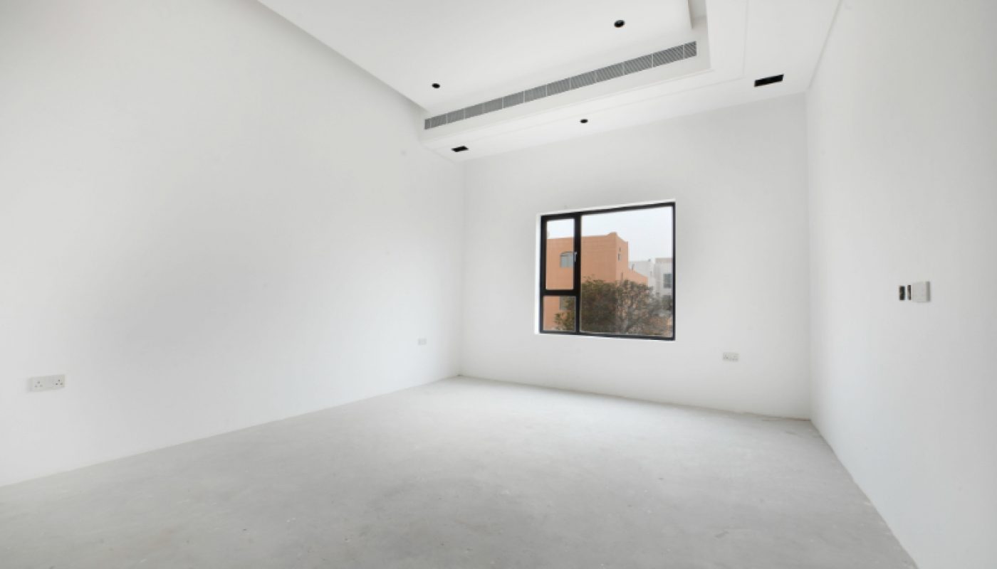 Empty, unfurnished white room with a single window, recessed lighting, and an air conditioning vent on the ceiling. Natural light enters through the window.