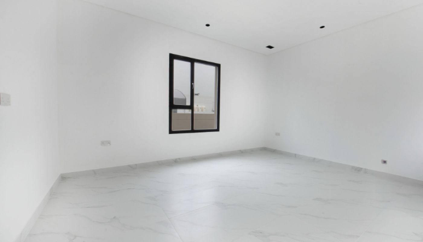 Empty, unfurnished room with white walls, marble tile flooring, a single window, and ceiling light fixtures. Natural light is coming in through the window.