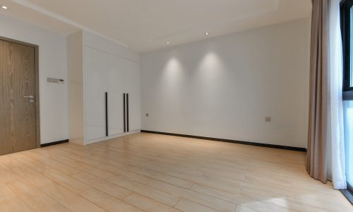 An empty room with wooden floors and a door in a stunning 3BR apartment for sale.