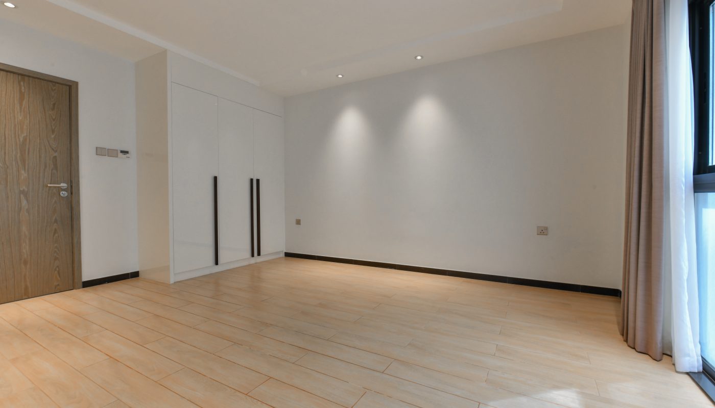 An empty room with wooden floors and a door in a stunning 3BR apartment for sale.