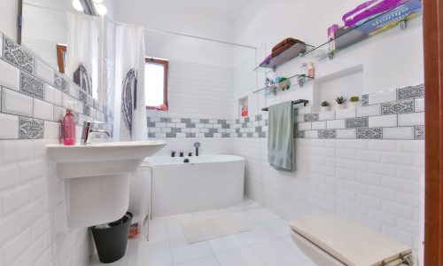 A stunning white tiled bathroom with a toilet and a sink.