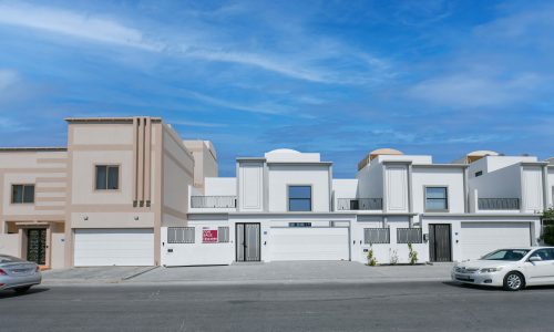 A row of houses with cars parked in front of them.