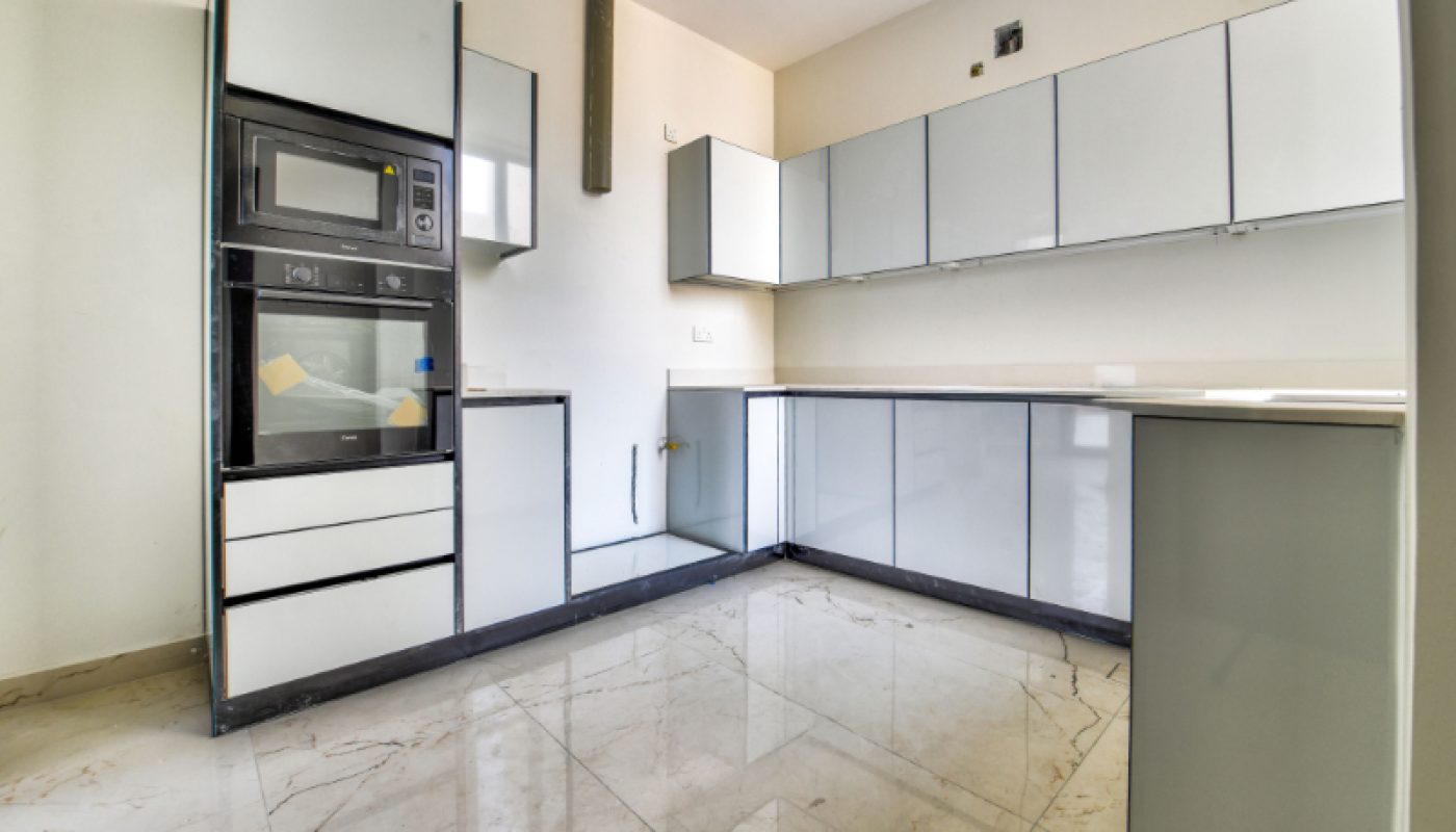 Modern kitchen with glossy white cabinets, built-in oven and microwave, marble floor, and minimalistic design.