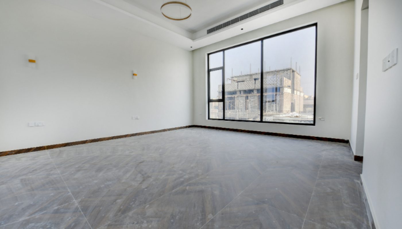 Empty room with tiled floor, white walls, ceiling light fixture, large window, and view of adjacent building under construction.