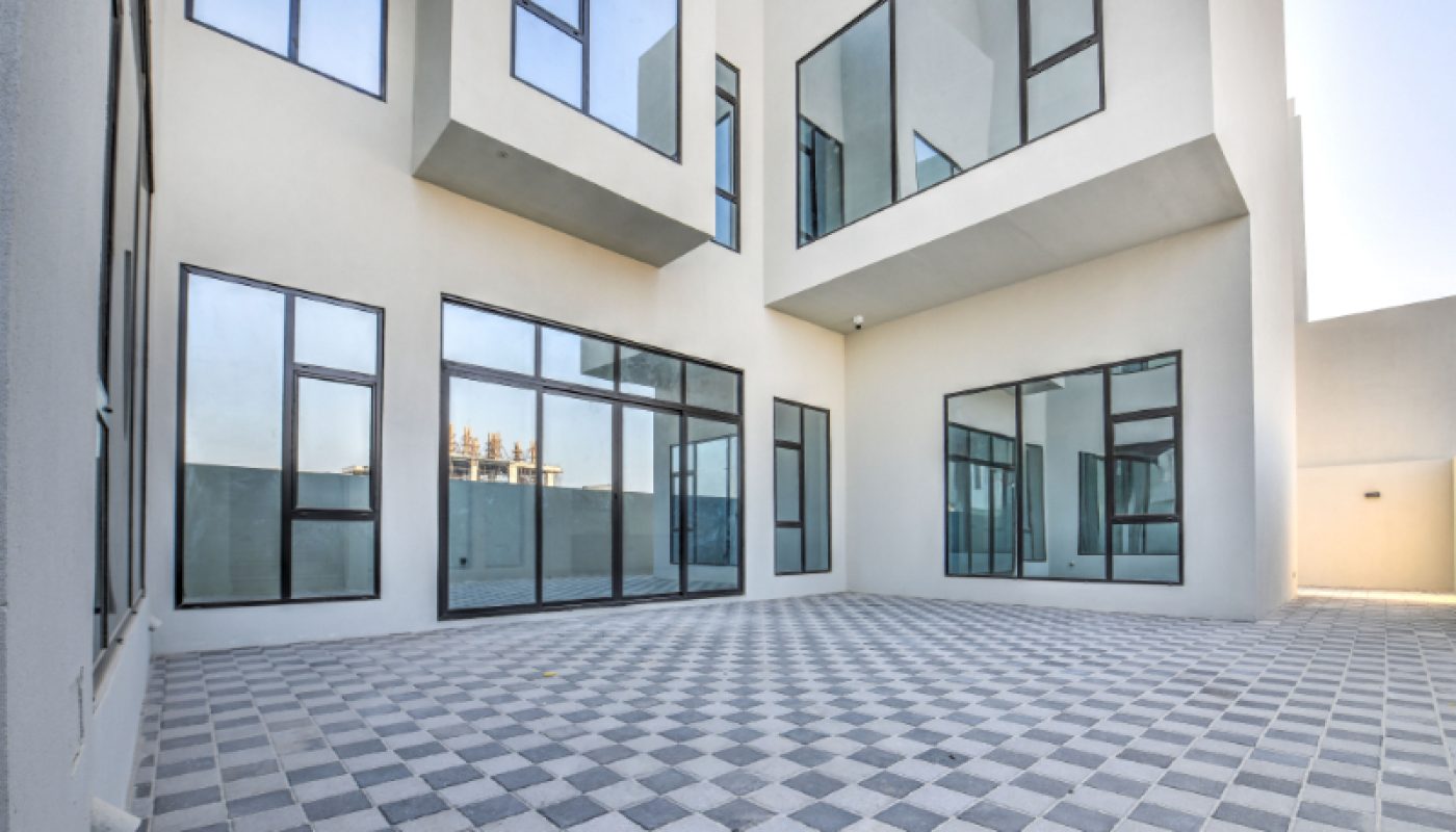Modern building exterior with large glass windows and white walls, featuring a spacious courtyard with a checkered tile floor.
