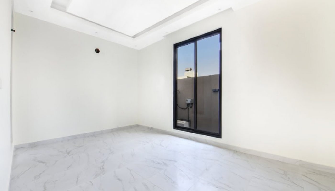 Empty room with white walls and a marble floor, featuring a large window with a view outside.