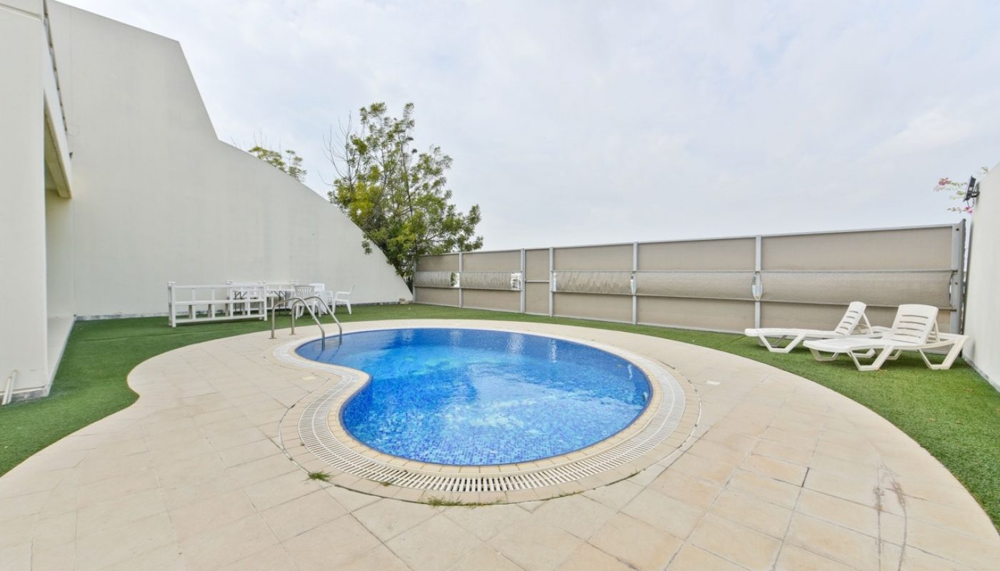 A luxurious swimming pool in the backyard of a large house.
