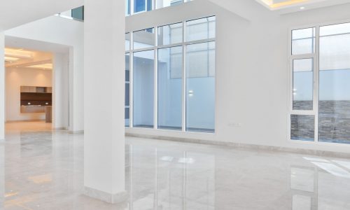 An empty living room with large windows and marble floors that is fully optimized for SEO.