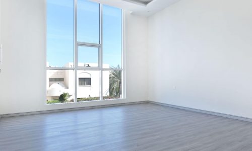 An empty room with wooden floors and a large window.