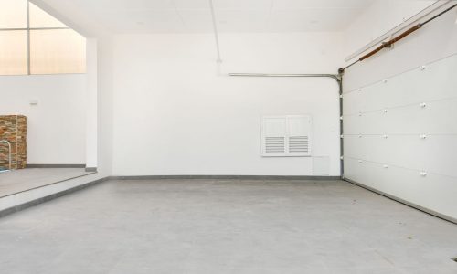 Empty garage with two Auto Draft doors and a stone wall.