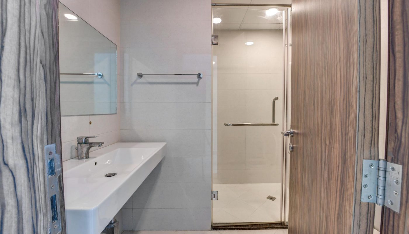 Modern bathroom with a wall-mounted sink, large mirror, towel bar, and a glass-enclosed shower area.