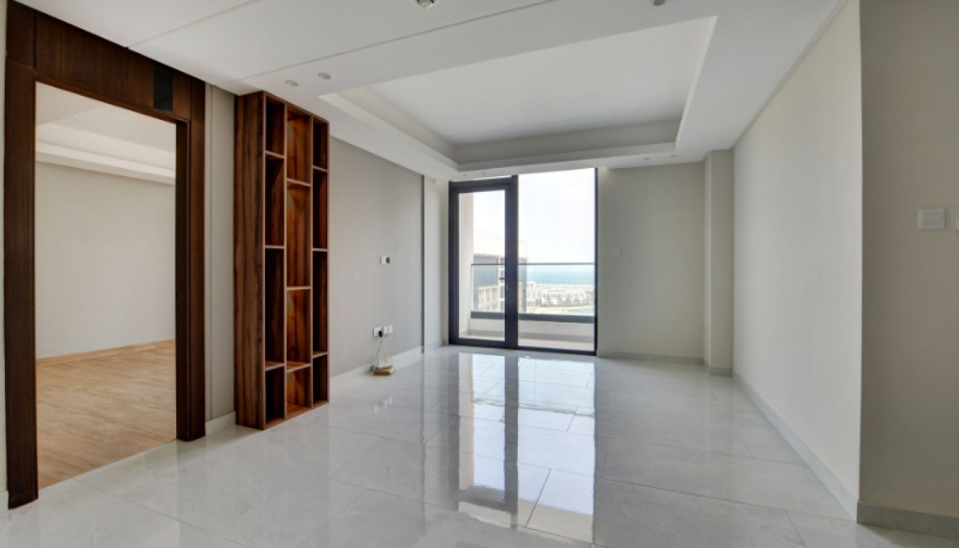 Unfurnished modern apartment with white tiled floors, sliding glass doors to a balcony, and a partial wooden room divider.