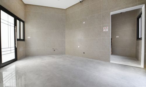 An empty room in a luxurious villa for sale, with a glass door and cement walls.