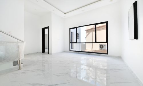 A luxurious villa for sale: a white house in Muqsha with marble floors and a glass door.