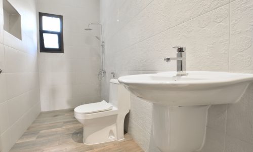 A white bathroom with a toilet and sink in a villa.