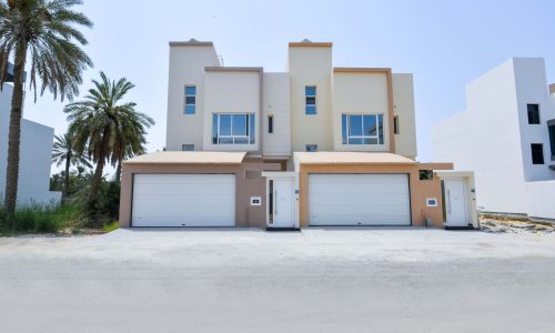 A villa with two garages nestled in a quiet location surrounded by palm trees.