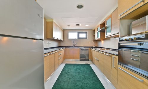 Modern kitchen interior with wooden cabinets and stainless steel appliances in a 5BR Villa for Rent.