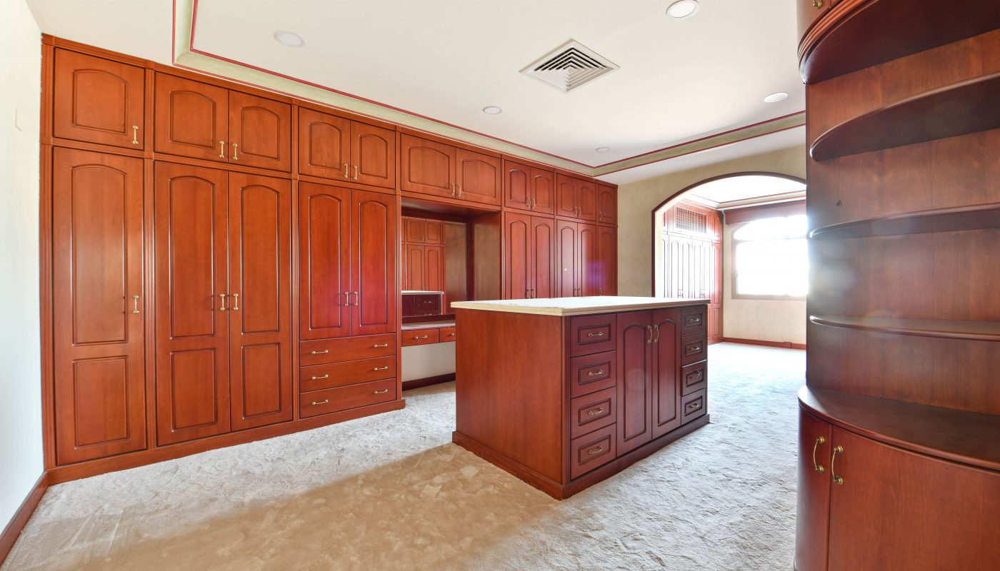 Spacious kitchen with extensive cherry wood cabinetry, a central island, and beige carpet flooring in a prestigious location.