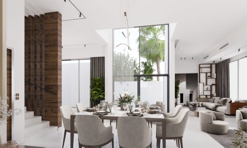 Modern dining area with a table set for eight, surrounded by upholstered chairs. Large windows provide natural light, revealing greenery outside. A well-designed space that serves as the perfect description of contemporary living, with stairs and a cozy living area visible in the background.