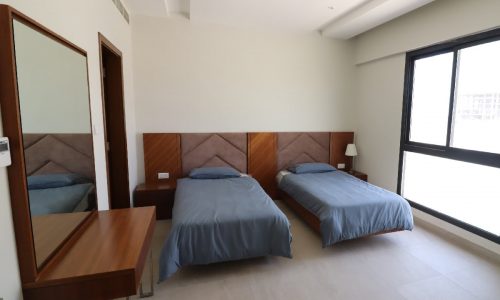 A mirror is featured in this exquisite bedroom with two beds.