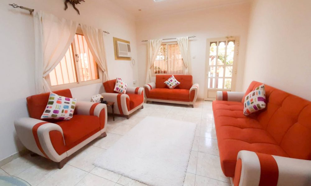 A luxurious living room with orange couches and a white table.