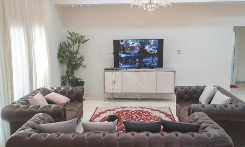 Luxury living room with couches and a TV in a 6BR villa for sale in Amwaj Area.