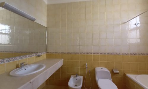 Luxury yellow tiled bathroom with toilet and sink in a 4BR Villa for Rent in Janabiyah within the Green Lash Compound.