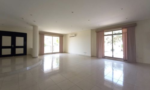 A modern and spacious living room with tile floors and sliding glass doors.