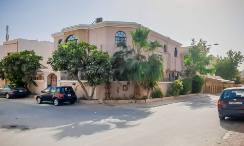 A elegant villa with cars parked in front of it.