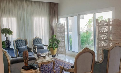 An opulent living area adorned with an embellished rug and luxurious chairs.