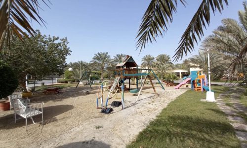 Luxury children's playground with palm trees and sand in Green Lash Compound.