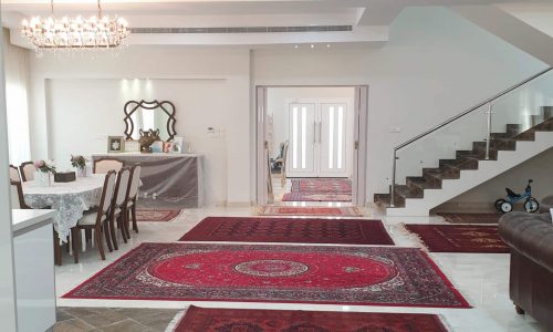 Luxury living room with red rugs and a staircase in Amwaj Area.