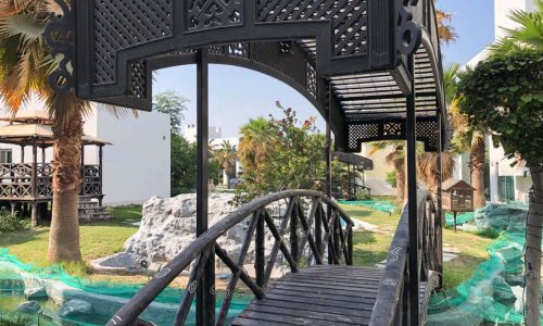 Lavish wooden bridge leading to a green area with palm trees in a 4BR Villa for Rent in Hamala.